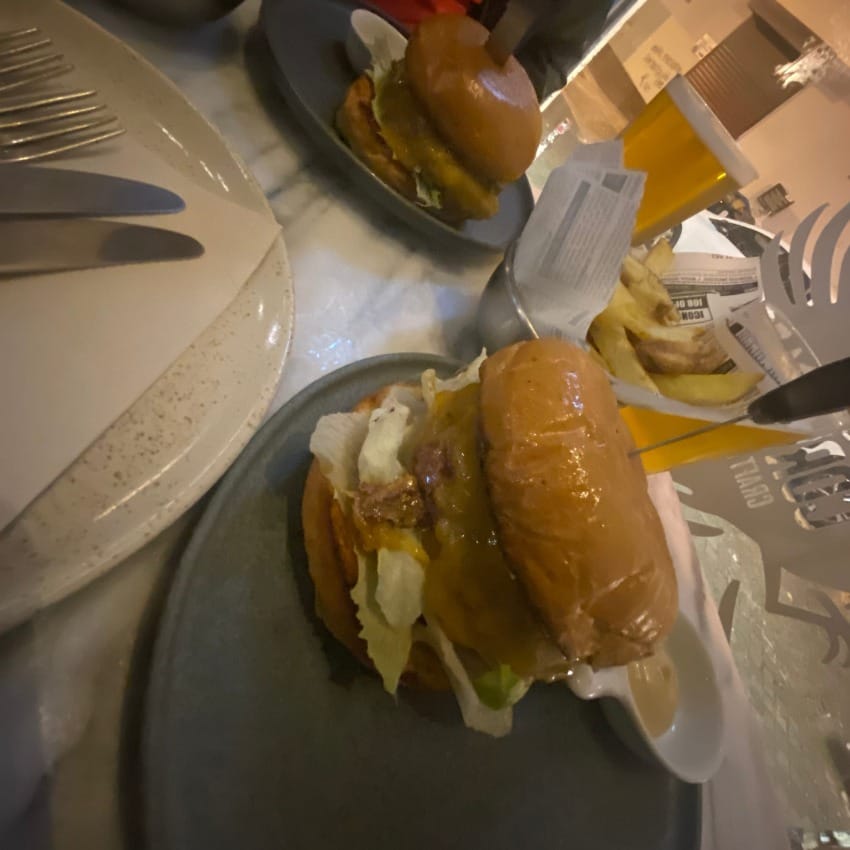 juicy cheeseburger with the top bun slid to one side and a pickle resting on the glistening melted cheese