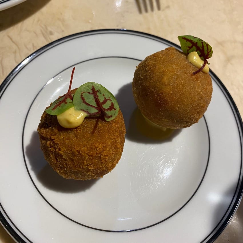 Two round bitesized leitão croquettes, smokey roasted piglet wrapped in breadcrumbs and deep fried