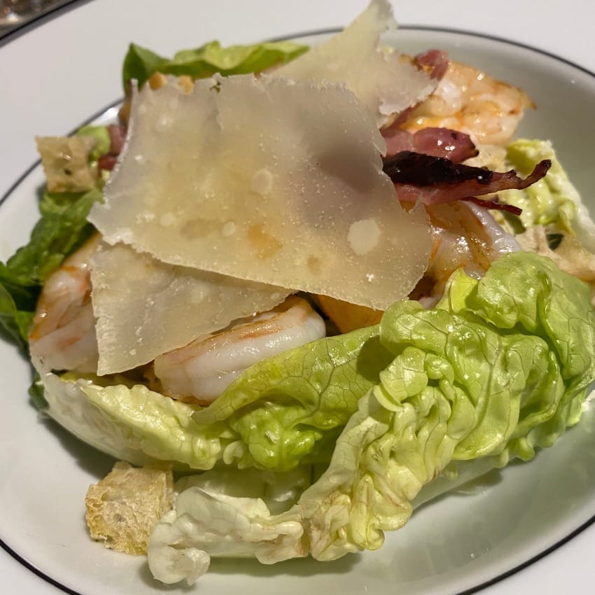 Huge shavings of parmesan sit across layers of caesar salad