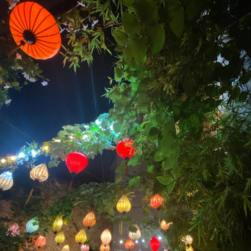 The open air ceiling of the garden dining area illuminated with traditional Vietnamese lamps