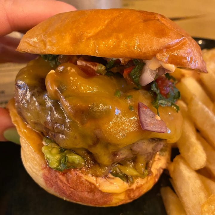 A very large cheese burger on a part brioche bun with guacamole