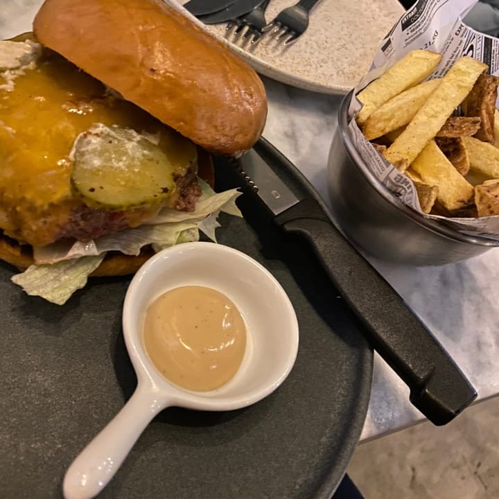 Cheeseburger with a bowl of skin-on fries and spicy dipping sauce, served together
