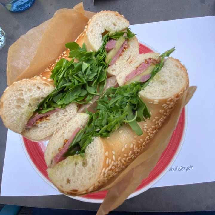 Brooklyn bagel: Seeded bagel filled with pastrami, pickle, mustard, and arugula, a classic deli-style sandwich