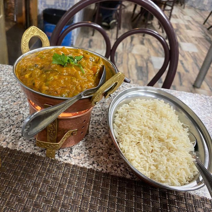 A bowl of spicy vegetable curry served with a separate bowl of rice