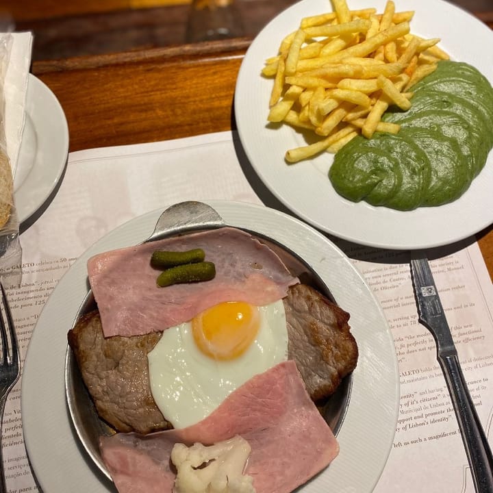 Sirloin steak topped with fried egg and ham, served with French fries and creamed green vegetables