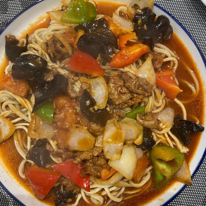beef and asian mushroom noodles in a spicy tomato sauce with onions and peppers